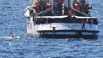Migrants jump off the Spanish rescue ship Open Arms, close to the Italian shore in Lampedusa